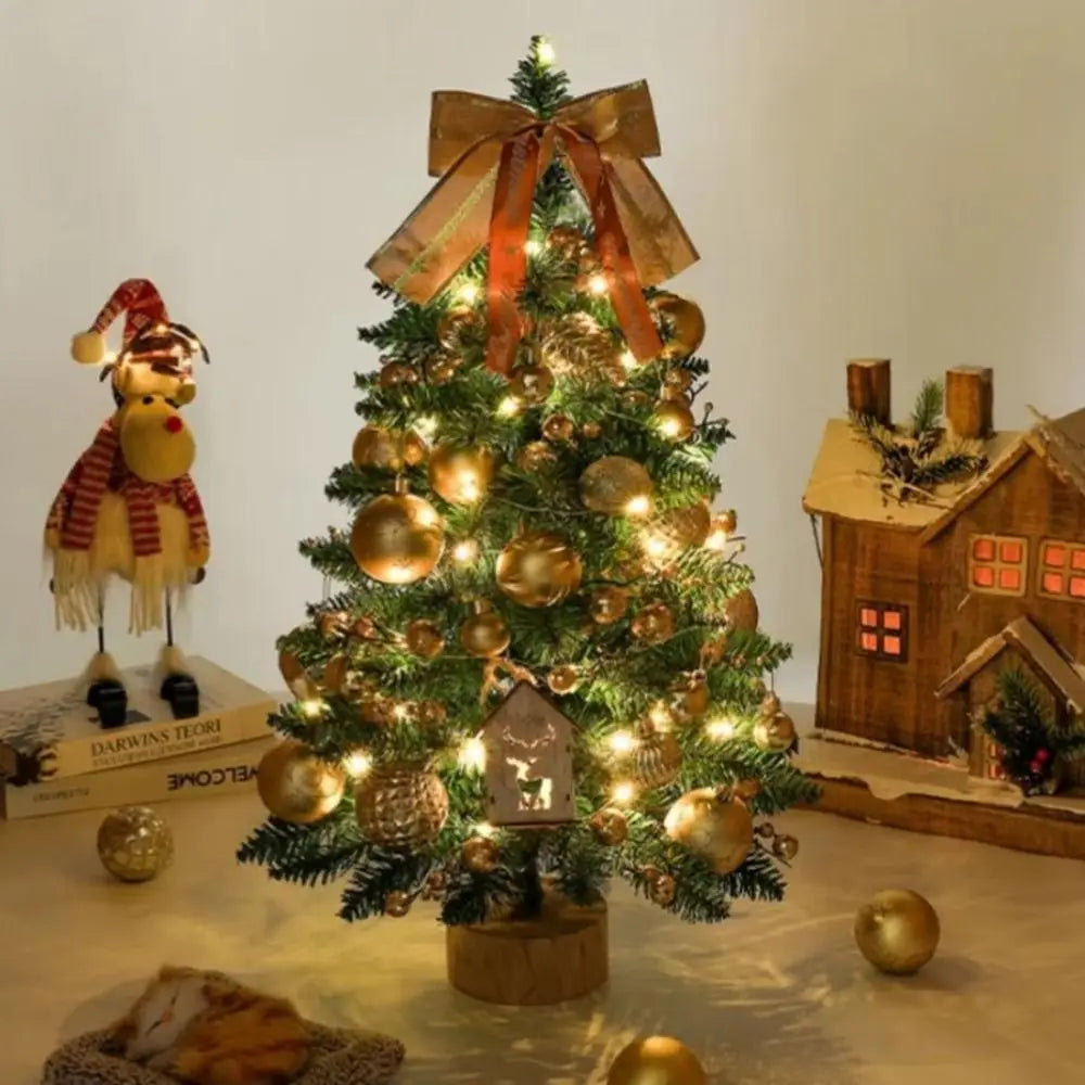 A small, decorated Christmas tree with warm LED lights sits on a wooden stand.