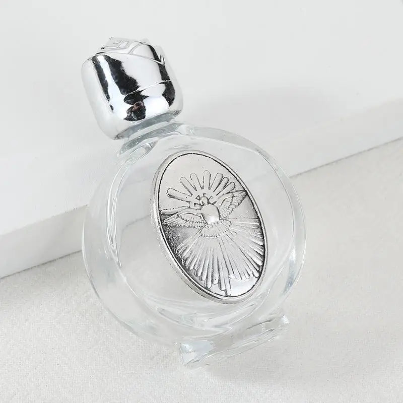 Decorative glass bottle with a silver figurine and a twist cap resting on a white surface.