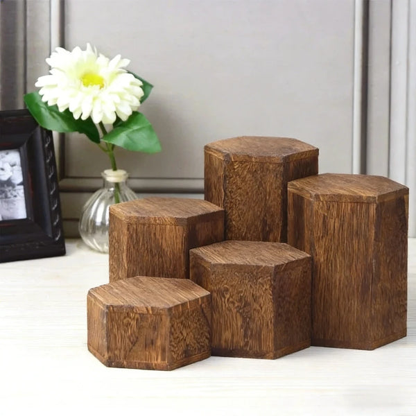 A stack of dark brown wooden hexagonal display racks for jewelry and accessories on a white surface.