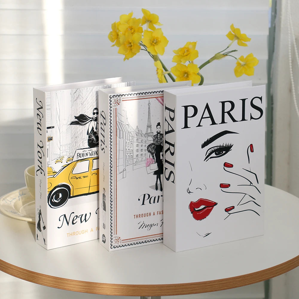 A set of three modern decorative fake books featuring yellow flowers and Parisian themes.