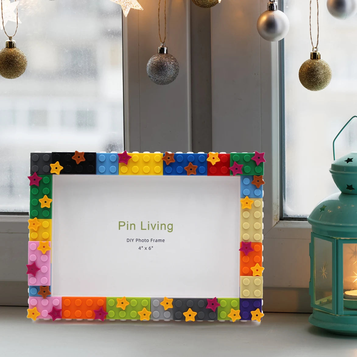 A colorful DIY photo frame made of decorative blocks with a white interior, displayed in front of a window.