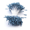 A cluster of small, blue artificial flower stamens with white filaments.