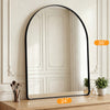 An arched full-length wall mirror with a matte black frame reflecting a room interior.