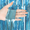 Hand holding a strip of silver metallic foil fringe curtain backdrop against a blue background