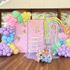 Pastel rainbow latex balloons in pink, yellow, and blue arranged for a first birthday party backdrop