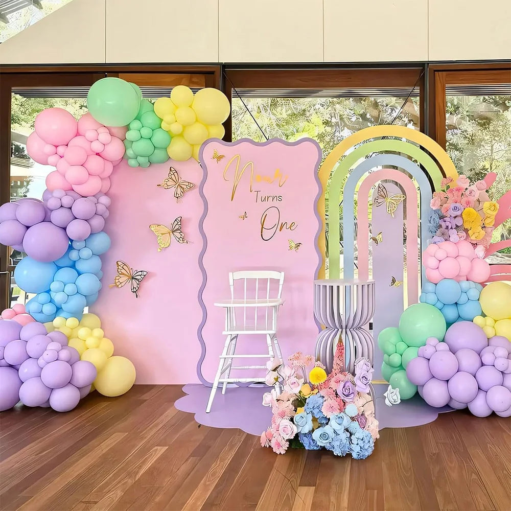 Pastel rainbow latex balloons in pink, yellow, and blue arranged for a first birthday party backdrop