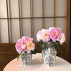 A floral arrangement of pink peonies in a blue and white porcelain vase set on a white table.