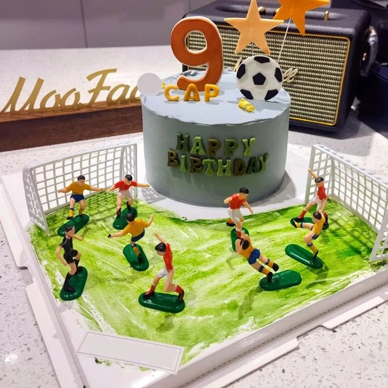 A birthday cake decorated with a number 9 and soccer players, set against a green field backdrop.
