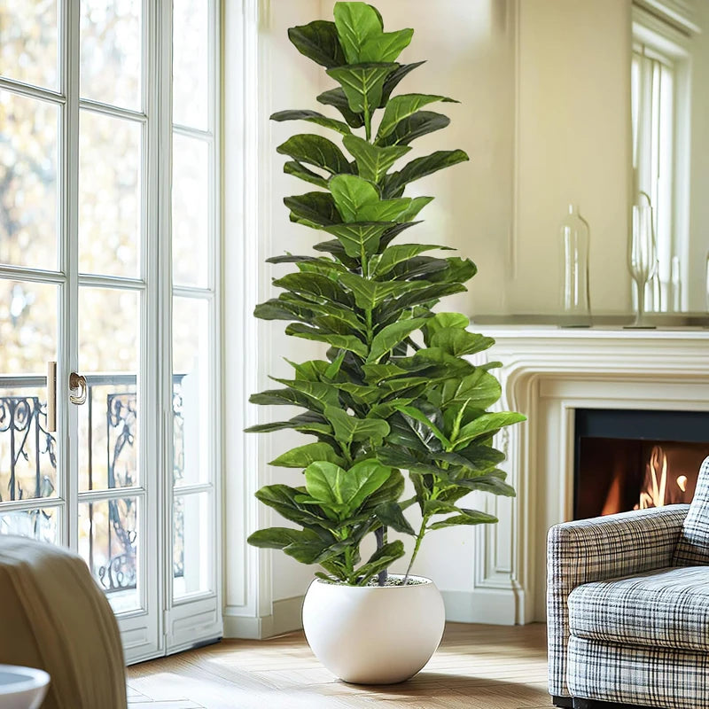 A tall artificial fiddle leaf fig tree in a white pot placed indoors next to a large glass door.