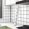 White and black grid peel-and-stick wallpaper covering a kitchen backsplash wall.