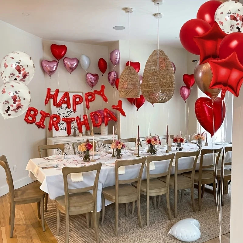 A table set for a birthday party decorated with red and pink star and heart foil balloons.