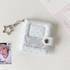 A clear plastic mini snap button photo album with a silver chain attached, featuring a decorative design and a clear window.