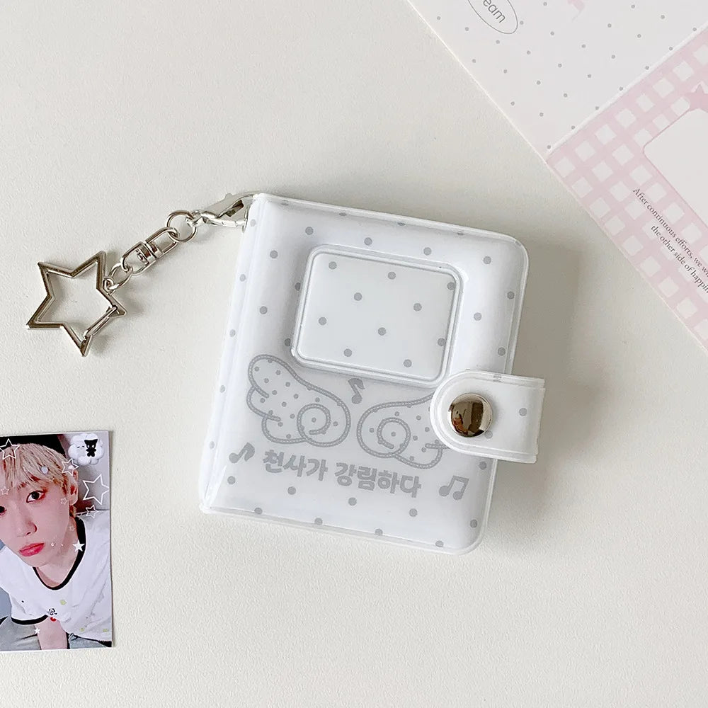 A clear plastic mini snap button photo album with a silver chain attached, featuring a decorative design and a clear window.