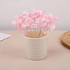 Pink bow cupcake toppers in a white cup displayed on a light surface.