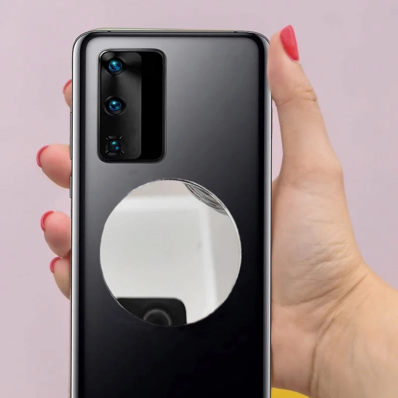 Una mano sostiene un smartphone negro que muestra un módulo de lente reflectante redondo.