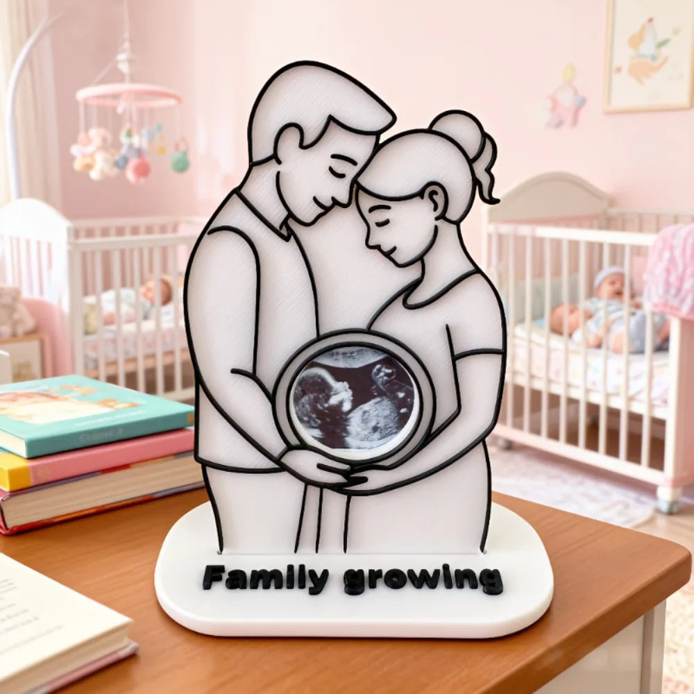 A white ultrasound photo frame keepsake ornament showing a family growing theme.
