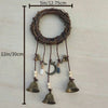 A rustic wreath with hanging bells and a crescent moon decoration on a wooden background.