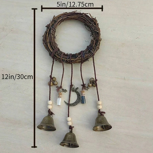 A rustic wreath with hanging bells and a crescent moon decoration on a wooden background.