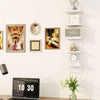 A modern white five-tier vertical wall shelf displaying framed art and decorative items.