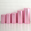 A row of four metallic pink spandex cylinder stands displayed against a white paneled wall.