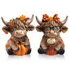 A set of two rustic wooden Highland cow figurines decorated with autumn leaves and pumpkins.