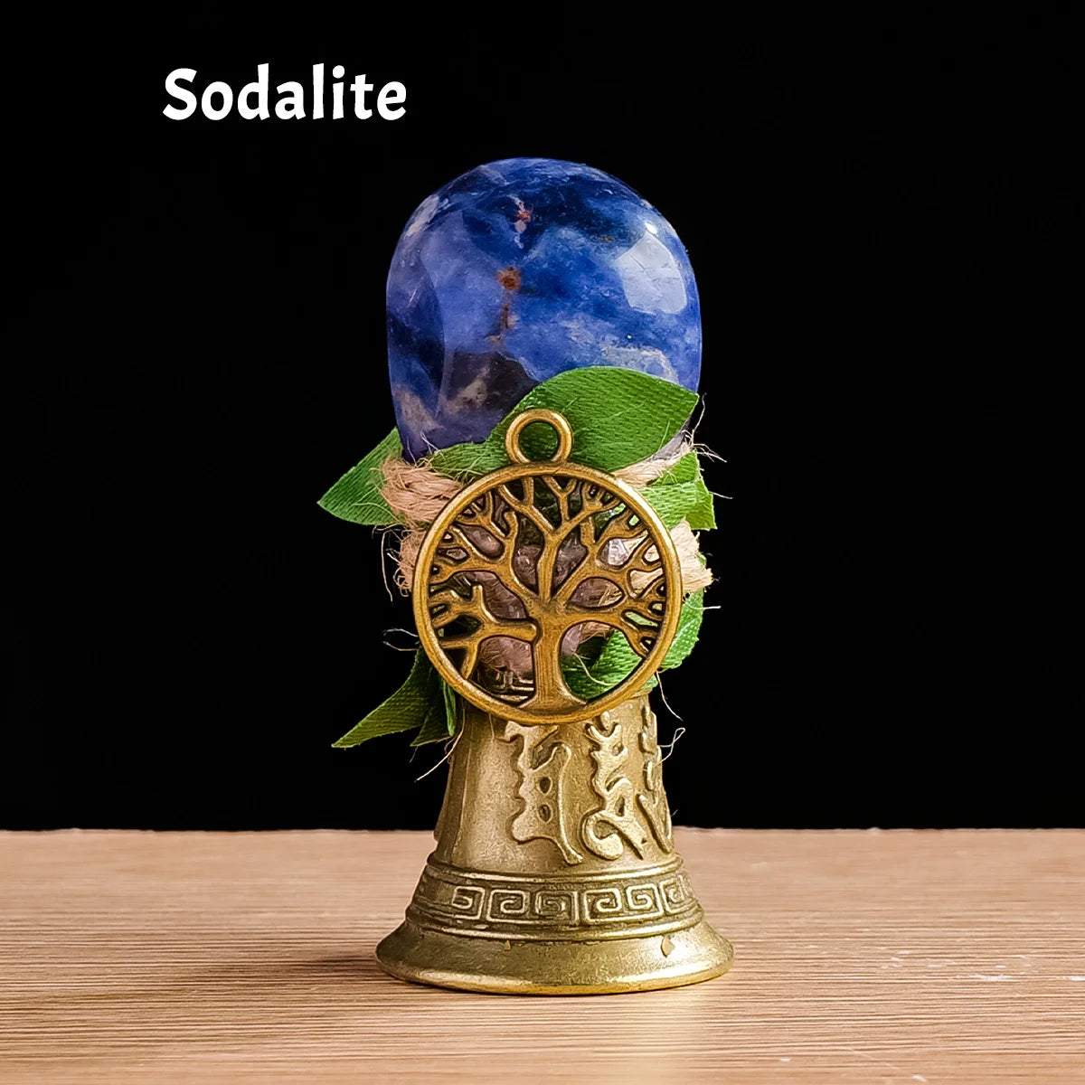 A blue sodalite crystal sphere rests atop a brass tree of life chime.