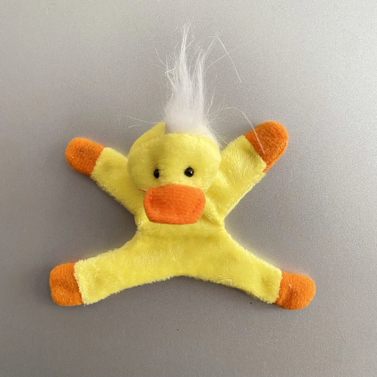A yellow plush toy shaped like a duck with orange accents and white feathers.