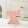 A pink ceramic bow candle holder with vertical ribbed texture sitting on a white surface.