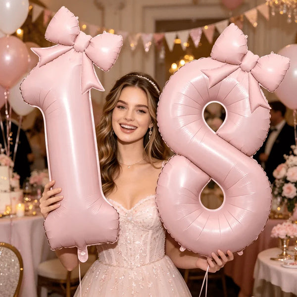 A young woman holds a large pink foil number balloon shaped like the number 8 with a bow.