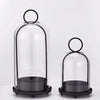 A set of antique brass metal candle holders with glass domes, shown in a vertical arrangement.