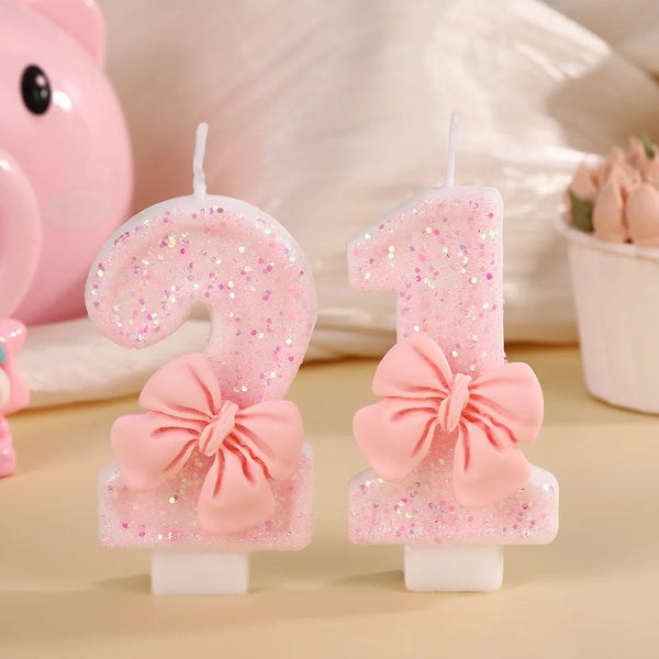 Un juego de seis velas de fiesta con lazos rosas y detalles de purpurina sobre un fondo claro.