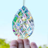 A faceted, iridescent crystal prism hanging by a thin string, held in a hand against a light blue background.