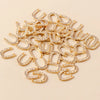 A pile of gold horse charm pendants for handmade jewelry, featuring various curved and horseshoe shapes.