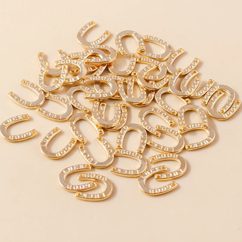 A pile of gold horse charm pendants for handmade jewelry, featuring various curved and horseshoe shapes.
