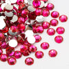 A pile of round flatback resin rhinestones in various shades of pink and red.