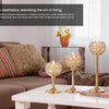 A set of elegant gold metal glass candle holders displayed on a white table next to a sofa.