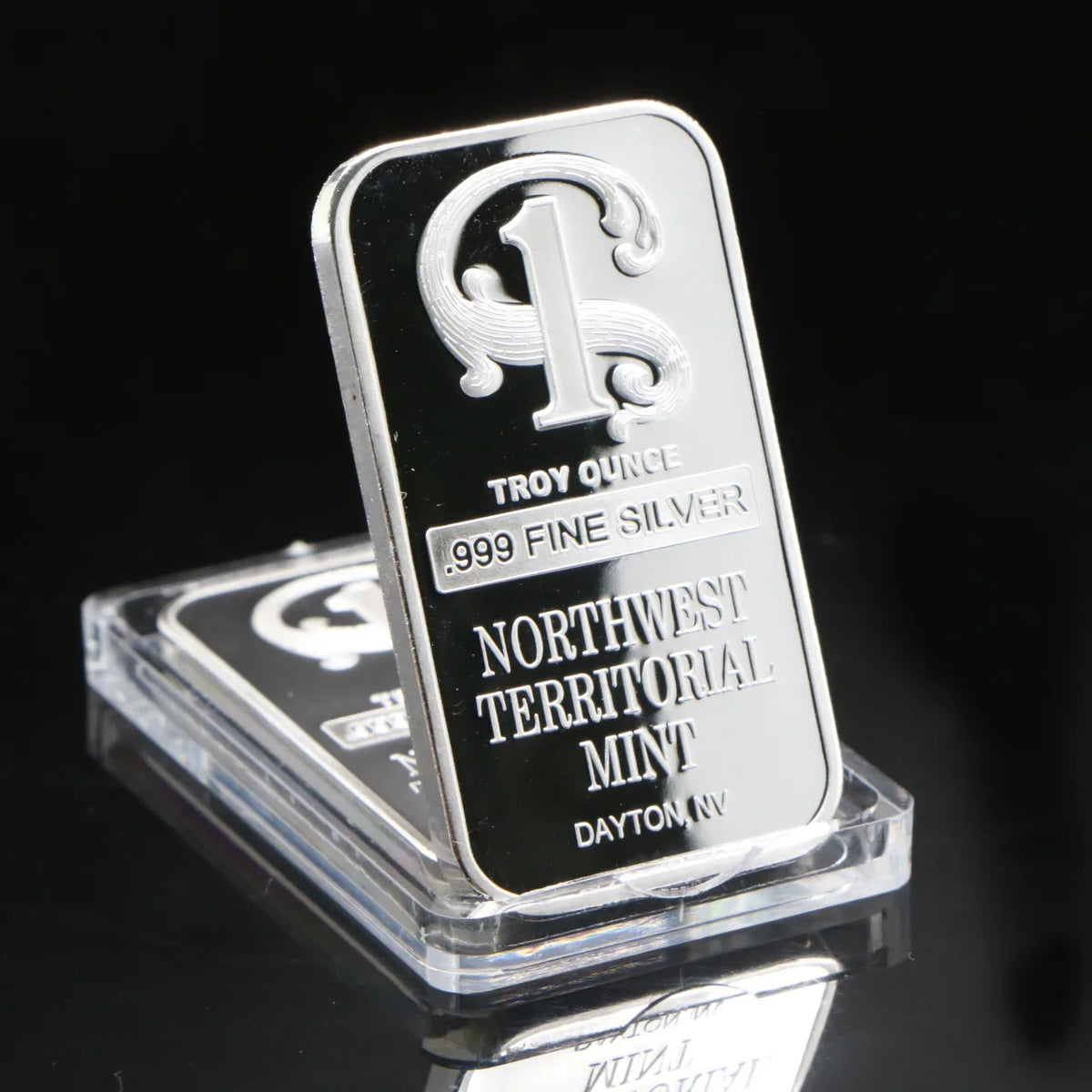 A silver Troy ounce fine silver mint bar with a stylized 'T' design, displayed in a clear plastic holder.