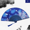 A blue and purple silk bamboo folding hand fan with floral patterns, shown open against a white background.