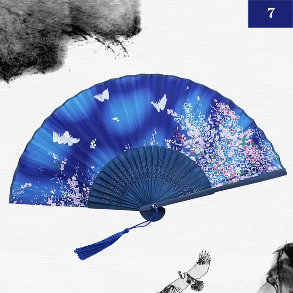 A blue and purple silk bamboo folding hand fan with floral patterns, shown open against a white background.