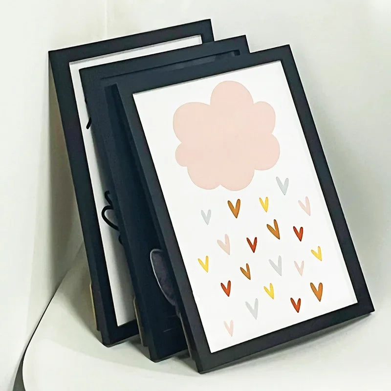 A set of three black picture frames with acrylic fronts displaying a pink cloud and scattered colored dots.