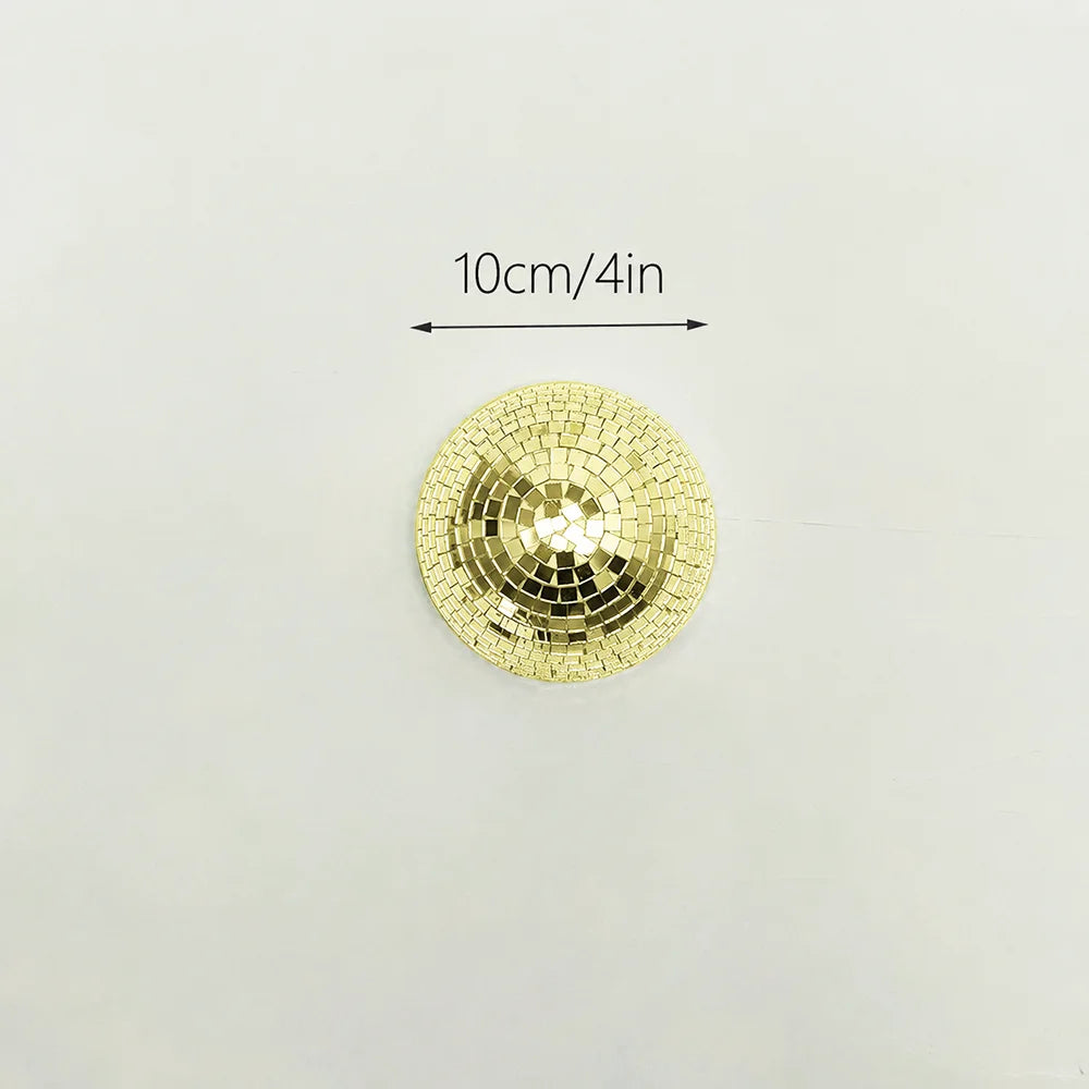 A round, gold mosaic disco ball decor mounted on a white surface, with a 10cm/4in scale marker.