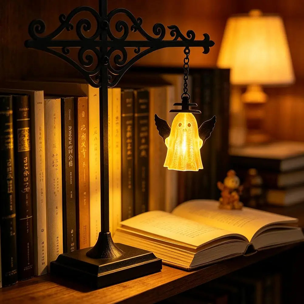 A black wrought iron lamp with a glowing yellow glass pendant hangs above an open book on a wooden shelf.