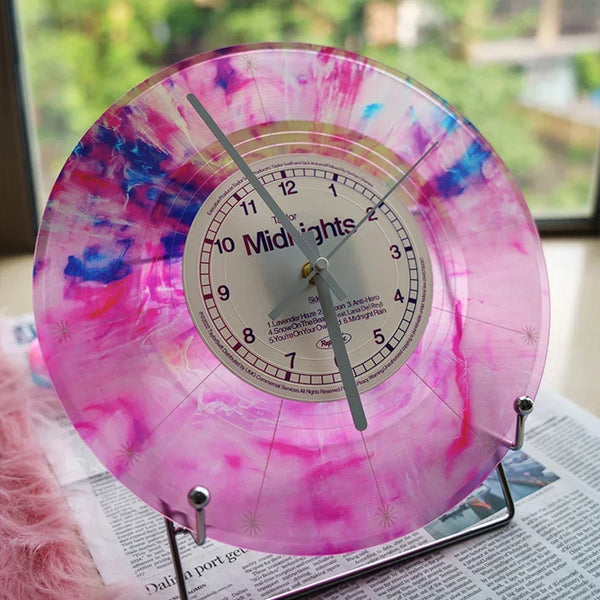 A vintage vinyl record wall clock with a transparent cover showing pink and purple swirling colors.