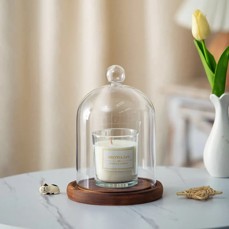 A glass aromatherapy candle holder with a white candle on a wooden base and dust-proof cover.