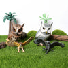 A figurine set featuring a realistic owl, vulture, and bald eagle perched on green grass with small plants.