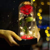 A hand holds a glass jar containing an LED simulation of a red rose with glowing filaments.