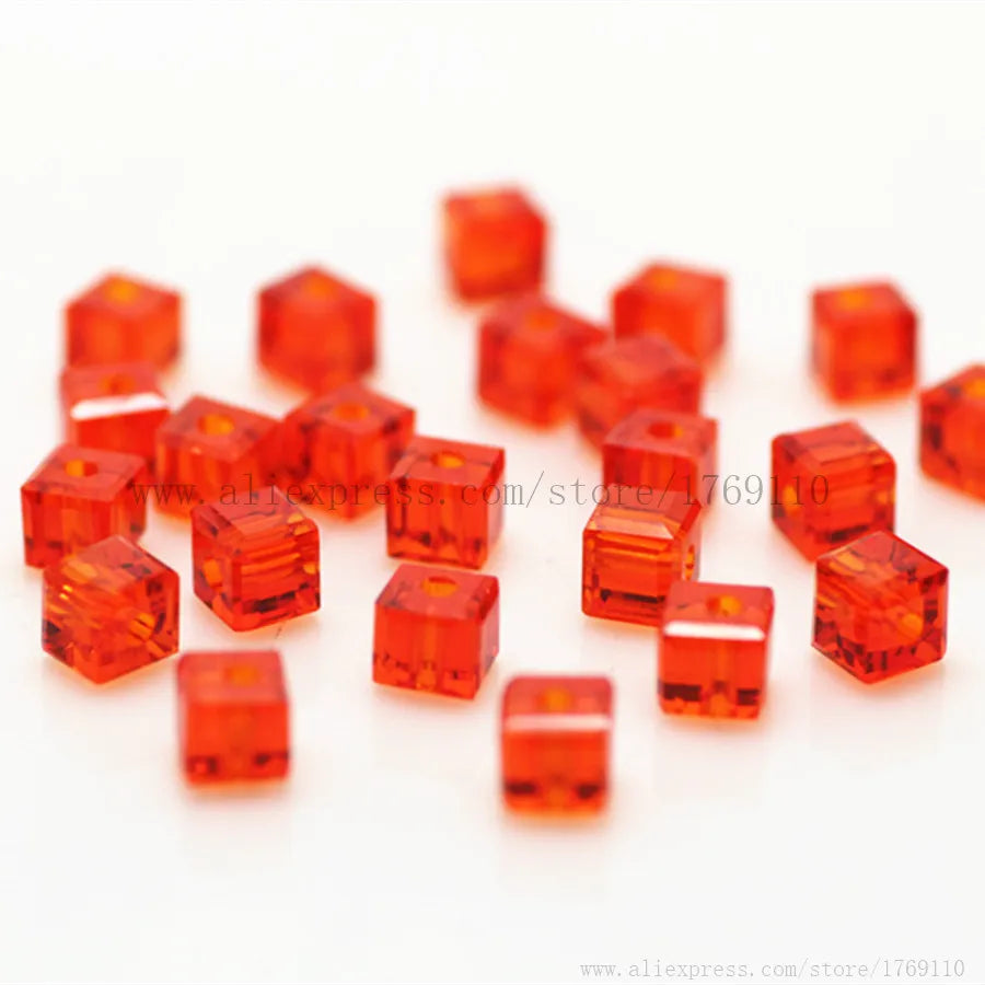A collection of square cut orange glass crystal beads for jewelry making scattered on a white surface.