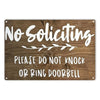 A wooden sign with white text that reads No Soliciting Please do not knock or ring doorbell