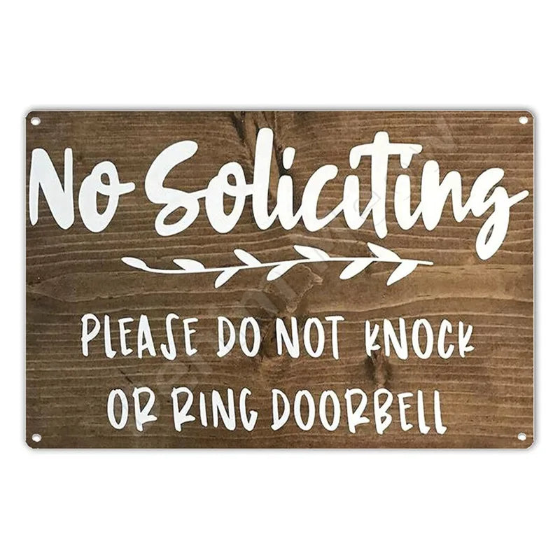 A wooden sign with white text that reads No Soliciting Please do not knock or ring doorbell