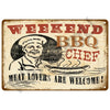 A vintage metal tin sign featuring a graphic of a smiling chef and text that reads Weekend BBQ Chef Meat Lovers Are Welcome